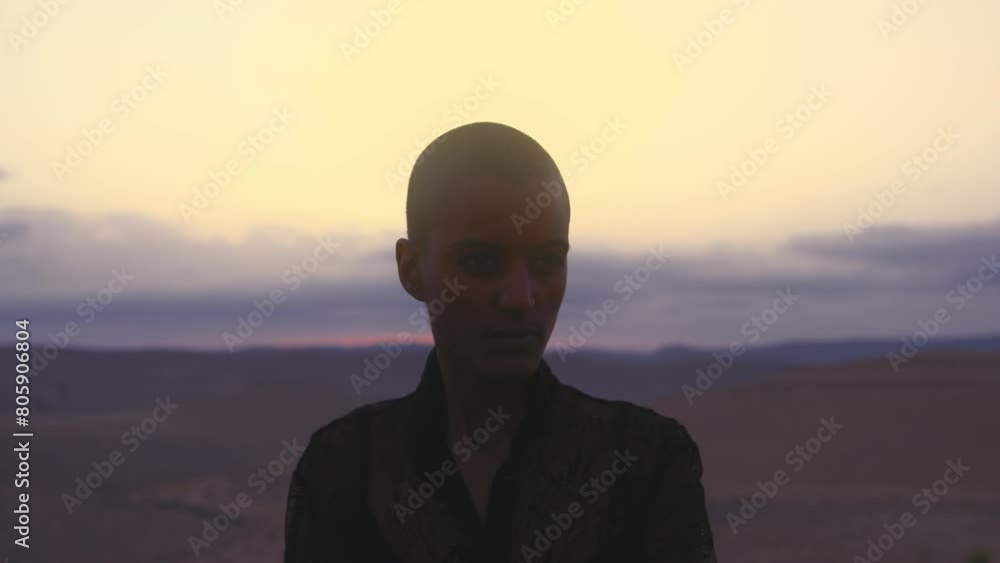 Model with shaved head posing in front of the camera in desert Model with shaved head posing in front of the camera in desert