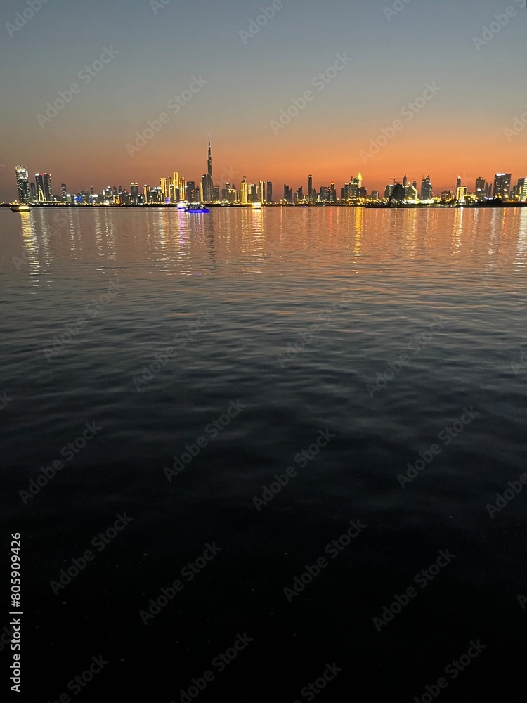 city river at the sunset time, down town silhouette at the background, orange sky, water reflection 