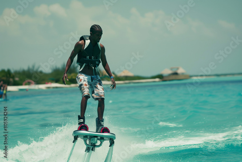 Young black man is flying at the aquatic flyboard. Water extreme sport photo