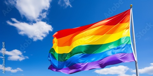 Vibrant rainbow flag waving against blue sky