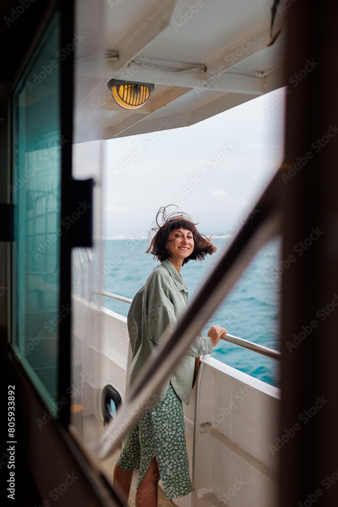 Obraz premium girl stands on the deck of a cruise ship. The girl is traveling. A young beautiful brunette travels on a yacht.