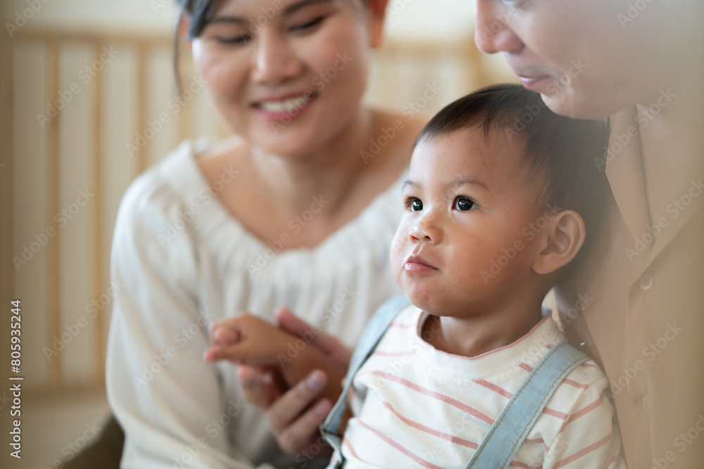 Warm moment of an Asian couple with their toddler in a softly lit room, reflecting family happiness and bonding. Warm moment of an Asian couple with their toddler in a softly lit room, reflecting family happiness and bonding.