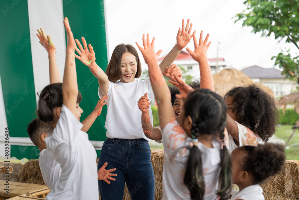 Diverse group of children with their teacher join hands during a creative group activity outdoors, smiling joyfully. Diverse group of children with their teacher join hands during a creative group activity outdoors, smiling joyfully.