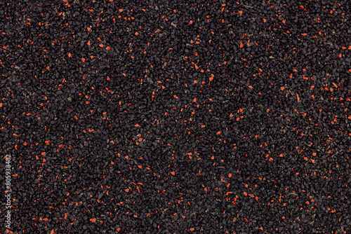 A black and red surface with many small red dots. The surface is made of a material that is not very smooth
