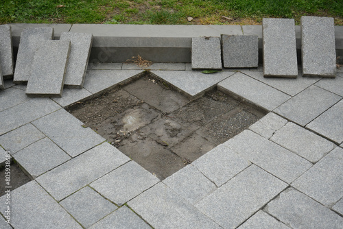 repairing tiled floor in city town. Gray stone sidewalk a and natural light in Batumi, Georgia. concrete border and green grass. land under grey granite tile.