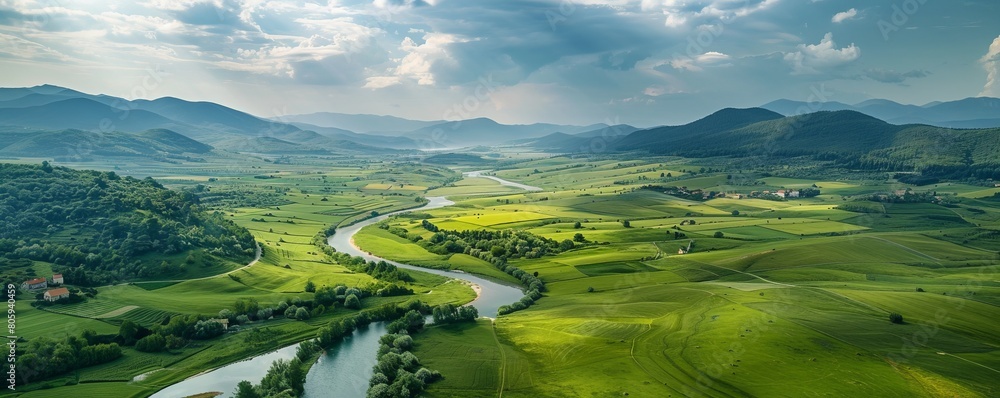 Aerial view of Udbina, Croatia with green meadows, winding river, and cloudy sky.