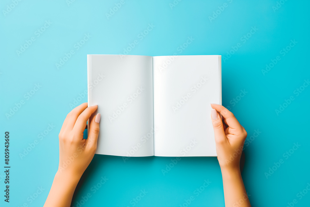 Woman hands holding folded blank paper sheet, empty booklet, double-pages book, magazine on light blue background. Mock up template. Top view Woman hands holding folded blank paper sheet, empty booklet, double-pages book, magazine on light blue background. Mock up template. Top view