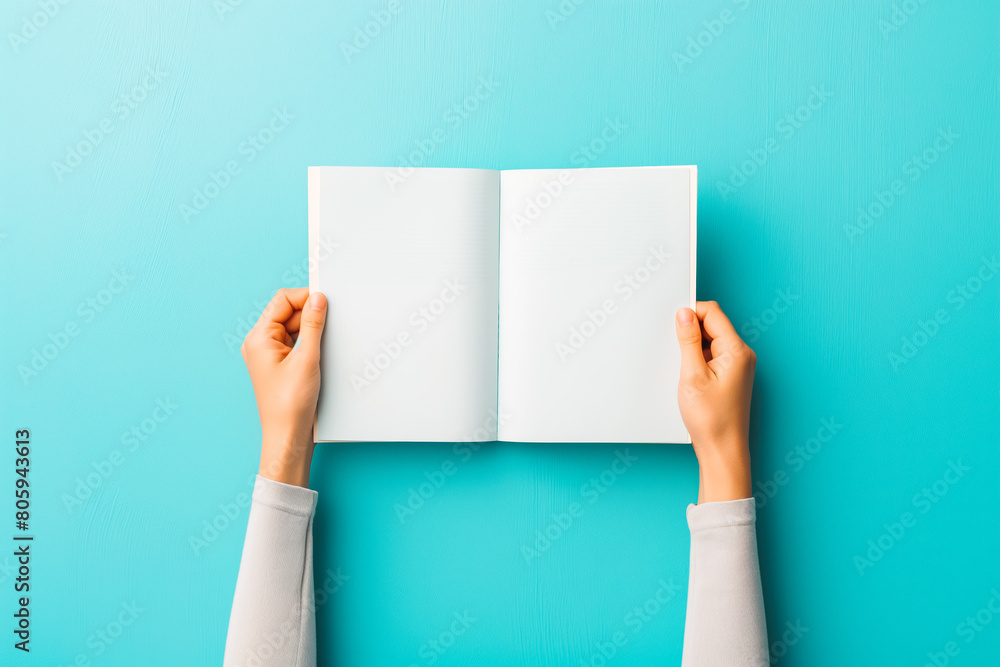 Woman hands holding folded blank paper sheet, empty booklet, double-pages book, magazine on light blue background. Mock up template. Top view Woman hands holding folded blank paper sheet, empty booklet, double-pages book, magazine on light blue background. Mock up template. Top view
