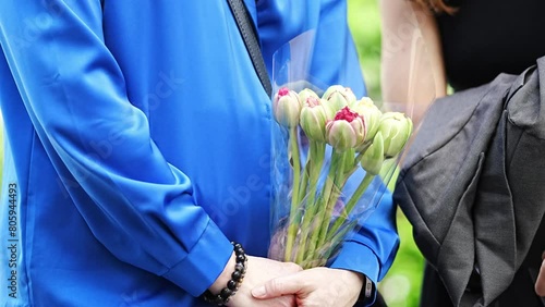 without a face. A woman in a blue blouse holds a bouquet of tulips in her hands. A gift for the holiday. photo