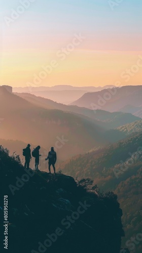 Hikers silhouetted on a mountain ridge at sunrise, overlooking a breathtaking vista of valleys and distant peaks