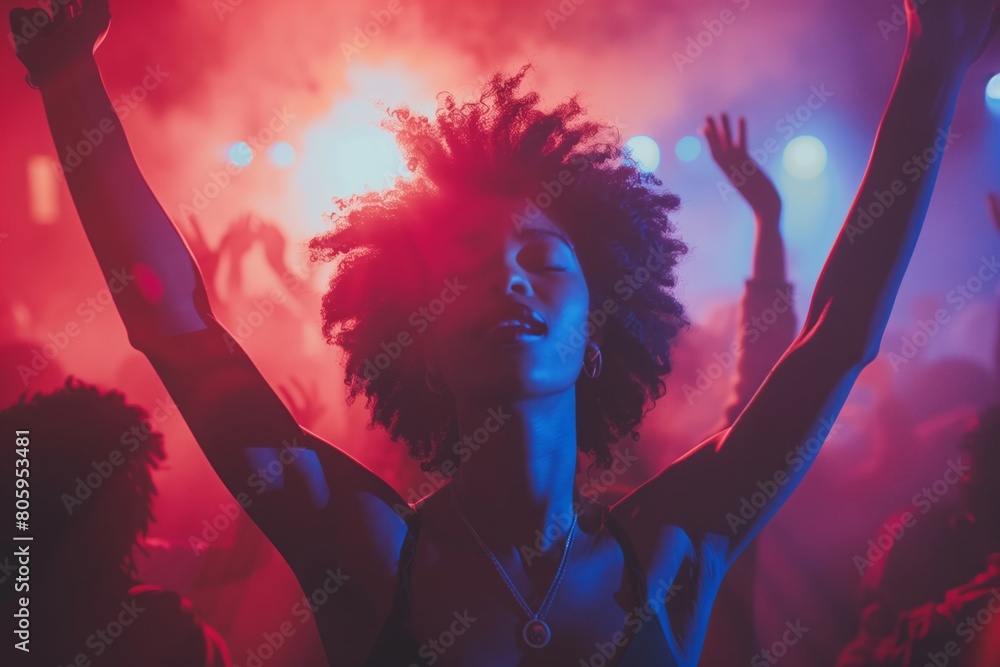 Silhouette of a young black girl with her arms raised on the dance floor of a nightclub