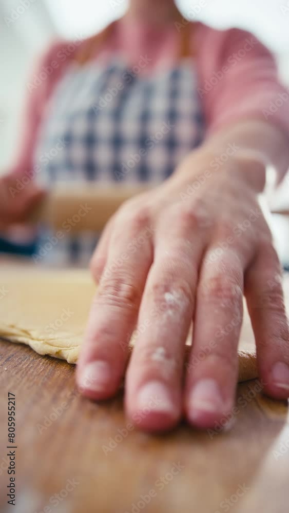 Close up vertical video of woman in kitchen rolling out dough with rolling pin on wooden board to make pasta - shot in slow motion Close up vertical video of woman in kitchen rolling out dough with rolling pin on wooden board to make pasta - shot in slow motion