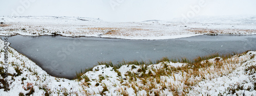Panorama view on a snow covered landscape with lake during a snow shower, Iceland
