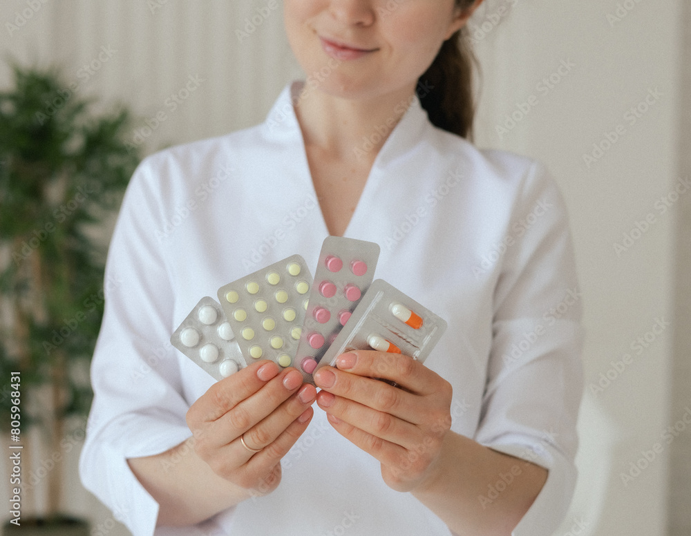 Medicine, healthcare and people concept - Close-up female gp physician doctor in white uniform is holding tablets and capsules in the clinic office. Part of a series Medicine, healthcare and people concept - Close-up female gp physician doctor in white uniform is holding tablets and capsules in the clinic office. Part of a series