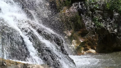 Falling water of a mountain river among stones.