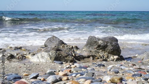 Sea waves crashing onto rocks on a summer day.