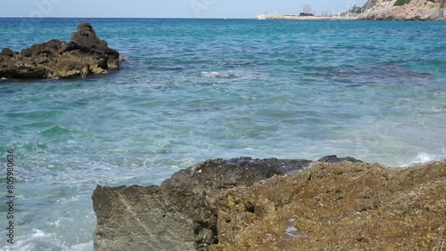 Sea waves crashing onto rocks on a summer day. Ship on the horizon.