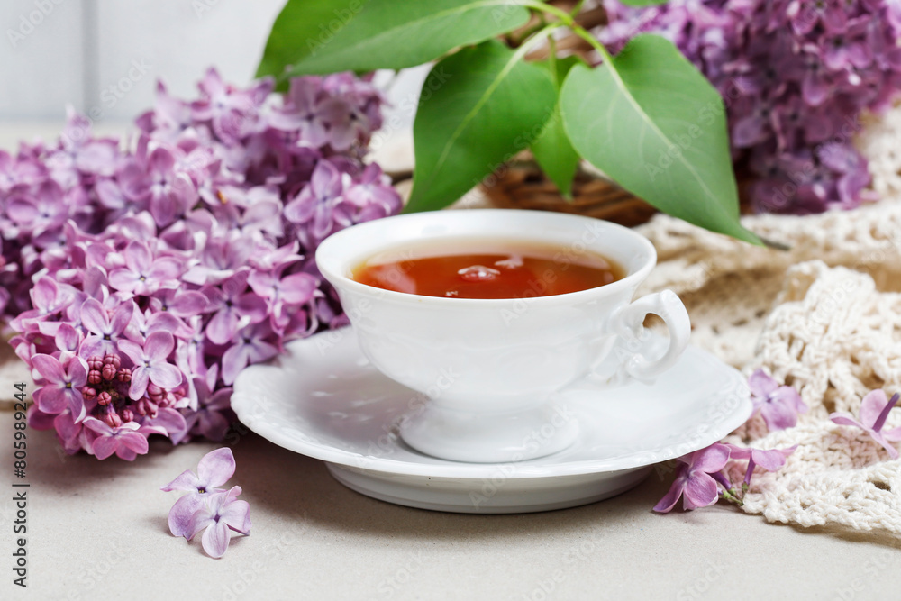 Porcelain cup with tea and lilacs in the background. Porcelain cup with tea and lilacs in the background.
