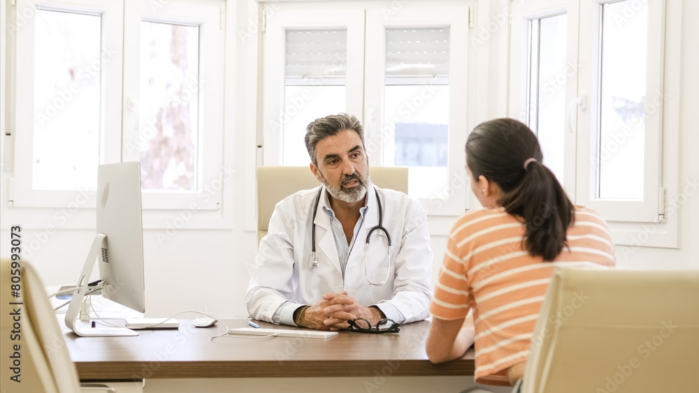 Confident doctor talking to female patient in clinic Confident doctor talking to female patient in clinic