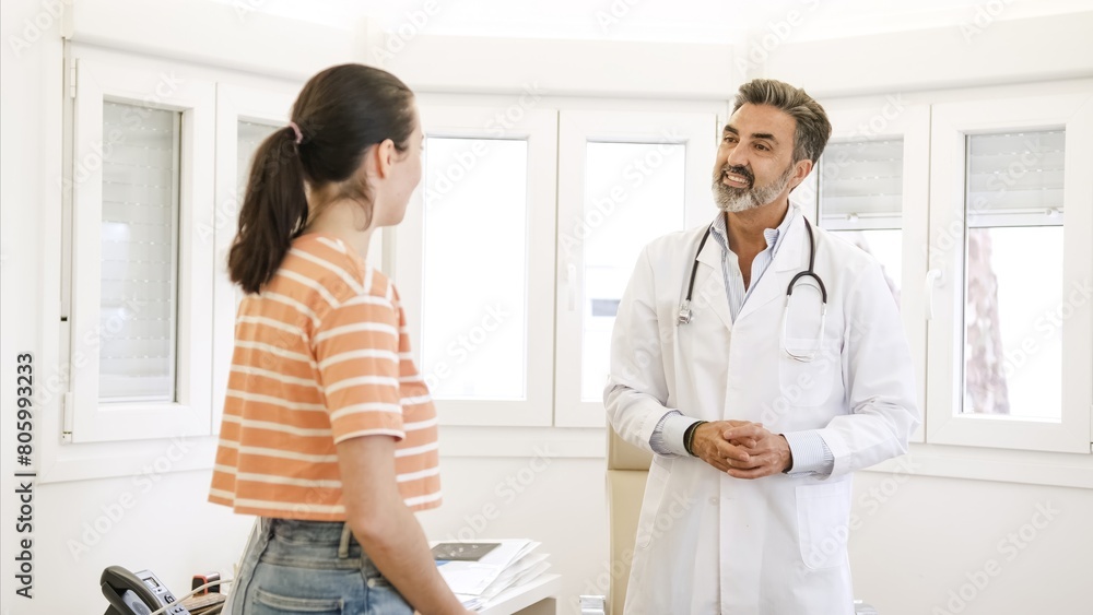 Fototapeta premium Happy male doctor talking to female patient in hospital