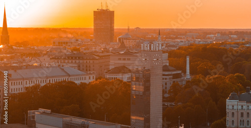 Aerial panoramic sunset over Riga old town in Latvia. Beautiful spring sunset over Riga. Riga clock tower close up view near the train station. Golden hour fire sunset.