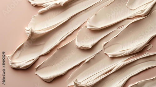 Abstract close-up image of creamy beige brush strokes layered on a soft pink background, creating a smooth, artistic pattern.