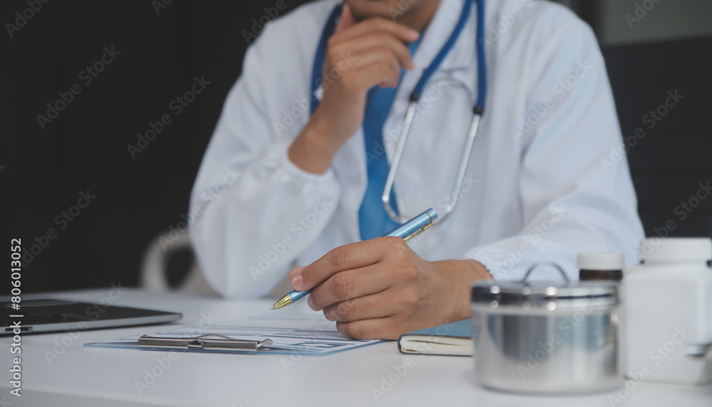 A professional and focused Asian female doctor in scrubs is working and reading medical research on her laptop in her office at a hospital. A professional and focused Asian female doctor in scrubs is working and reading medical research on her laptop in her office at a hospital.
