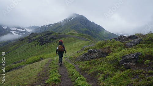 A traveler follows a trail leading to the mountain peak, where clouds blend with the sky, gaining a sense of infinity.