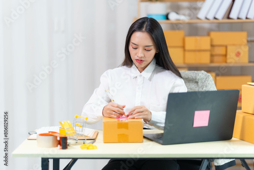  woman sit at workplace desk laughing working on-line using laptop in warehouse. 
