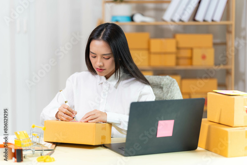  woman sit at workplace desk laughing working on-line using laptop in warehouse. 