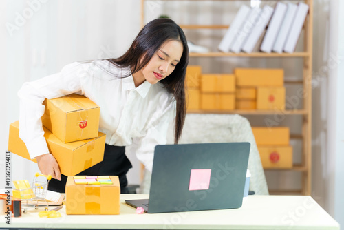  woman sit at workplace desk laughing working on-line using laptop in warehouse. 