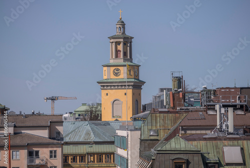 The tower of church Maria Magdalena kyrka, tin roofs, dorms on old houses at the sluice area in the district Södermalm, a sunny spring day in Stockholm