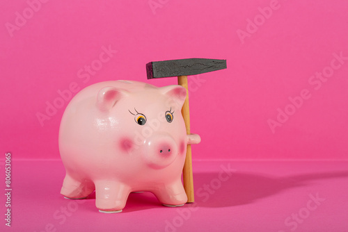 Pink piggy bank with small hammer