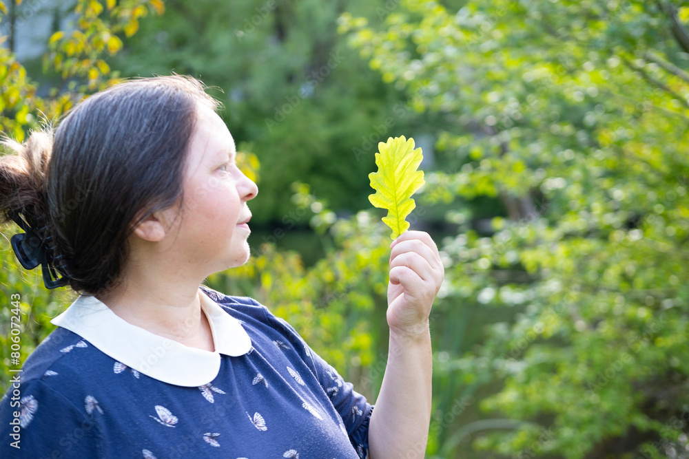 mature woman holding oak green leaf, active lifestyle for health, rejuvenating power nature, woman's holistic approach to health, Eco-friendly living mature woman holding oak green leaf, active lifestyle for health, rejuvenating power nature, woman's holistic approach to health, Eco-friendly living