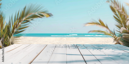 a wooden white table at the sandy beach with palms on the background for minimalistic summer idea banner