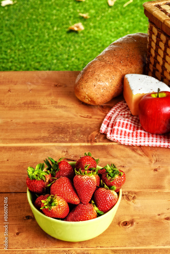 picnic table with a green bowl of strawberries