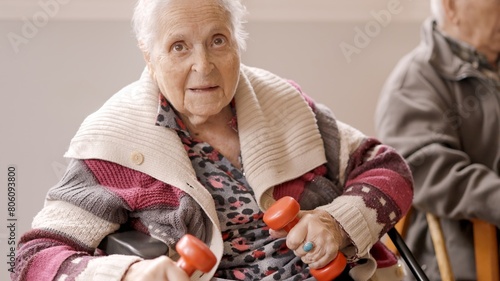 Old woman exercising with dumbbells sitting on a nursing home