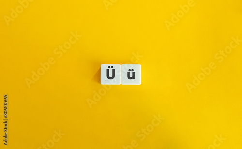 Capital and Small Letter Ü. Uppercase and Lowercase Letter. Concept of Learning Alphabet. Text on Block Letter Tiles against Yellow Orange Background. photo