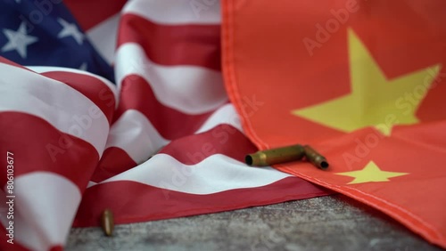 Unrecognizable person's hand picking up a handful of bullets of different sizes, amidst an American and Chinese flag