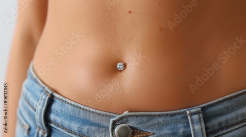 Close-up of woman's belly with sparkling navel piercing. Studio photography with focus on jewelry. Fashion and body art concept