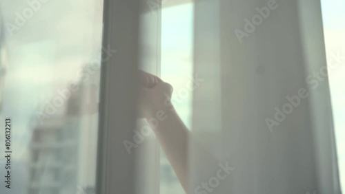 Opens a metal-plastic window.
A man opens a window to ventilate the room photo