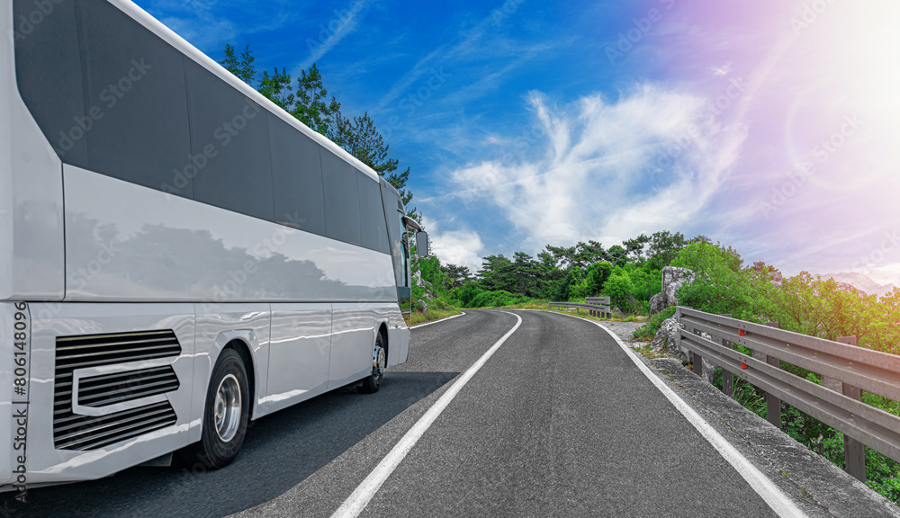 A white tourist bus travels along a picturesque mountain road. A white tourist bus travels along a picturesque mountain road.
