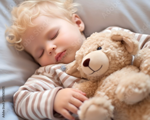 Blond child little boy sleeps like an angel in bed with a teddy bear