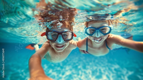 A wide-angle underwater photograph captures the joy of two children swimming and exploring in a large pool. Equipped with masks 