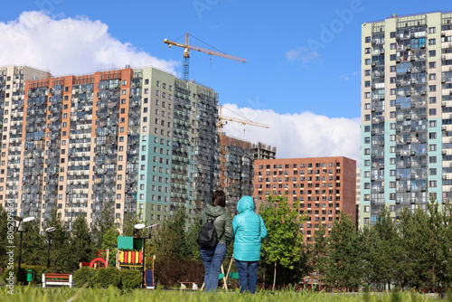 Photography Two women looking at the new houses of residential district and construction cranes