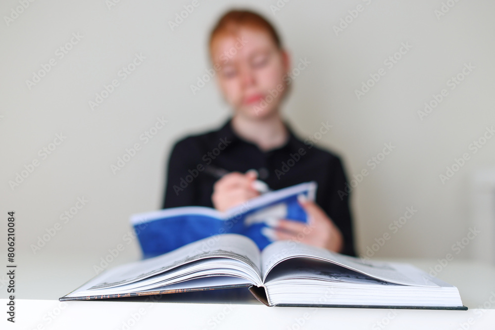 female student preparing for exams against the background of books, focus on the book female student preparing for exams against the background of books, focus on the book
