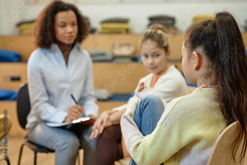 Back view of unrecognizable teen girl sharing mental health problems during support group meeting for children with copy space