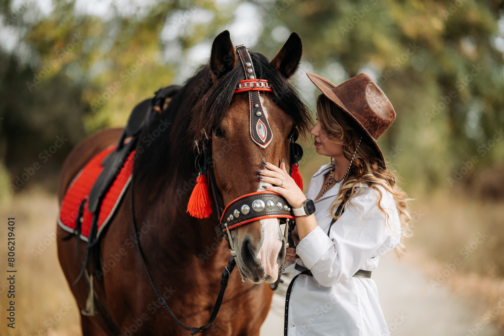 Obraz premium A girl in a white shirt and hat stands next to the horse.