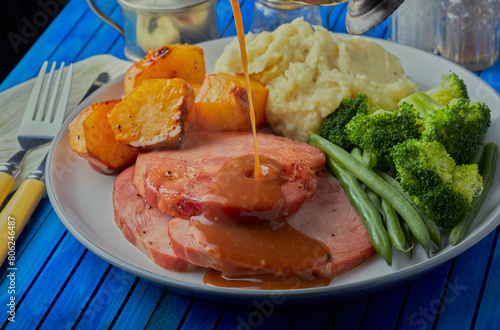 Gammon roast dinner with gravy being poured over it. © Mark