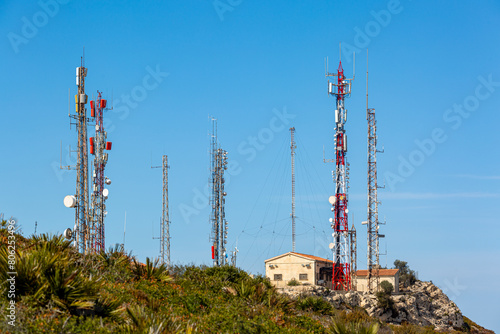 Telecoms masts and buildings on top of the mountain Puig de la Llorenca on a clear sunny day overlooking Cumbre Del Sol, Spain